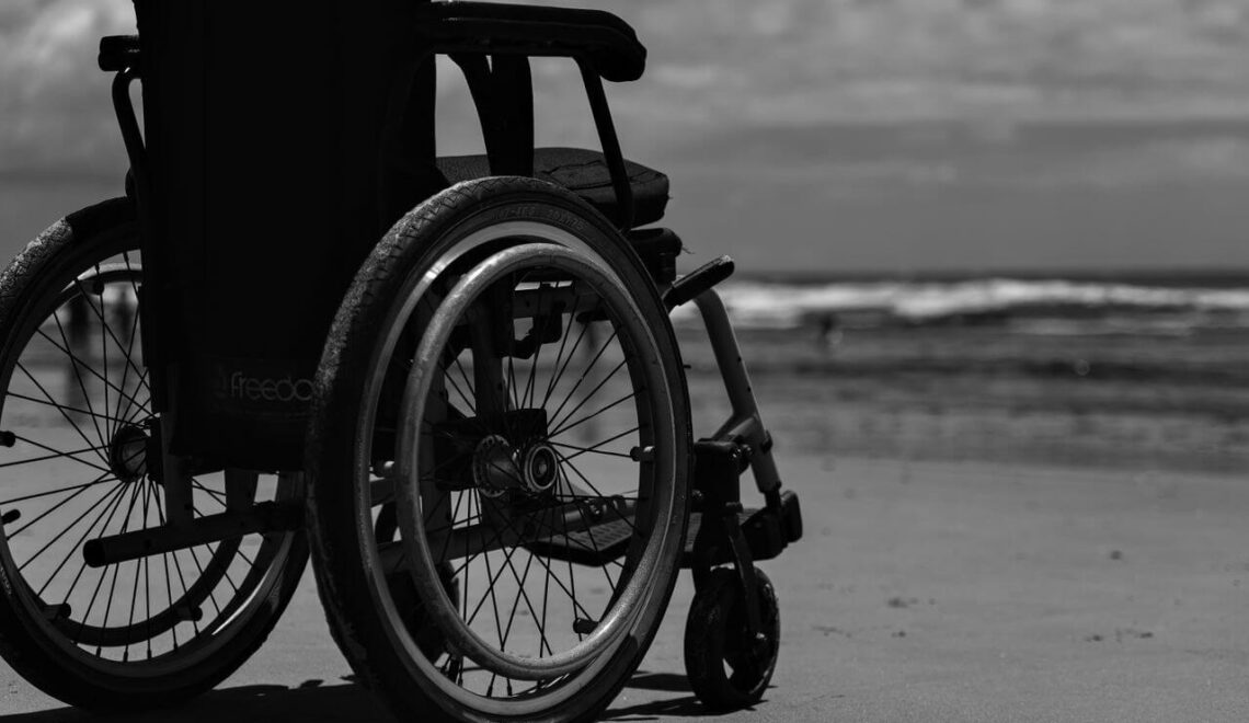 Rolstoel op het strand met uitzicht op zee, symbool voor mobiliteit en vrijheid